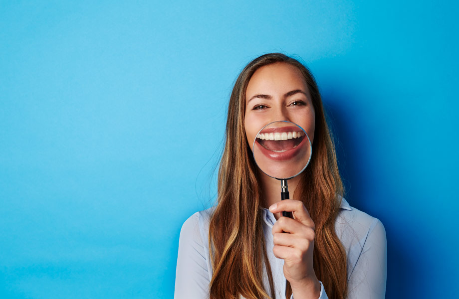 woman holding magnifying glass to mouth to see how oral health affects overall health