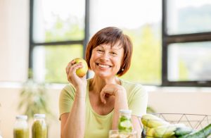 middle aged woman holding apple smiling