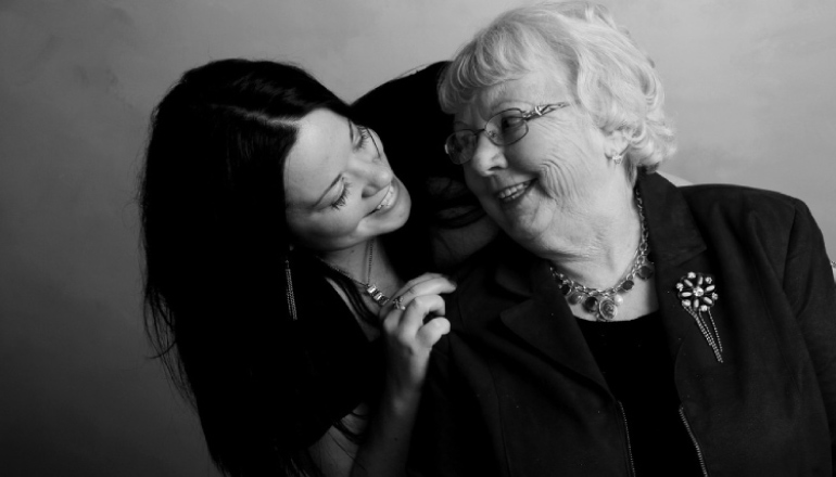 granddaughter leaning over smiling at her grandmother