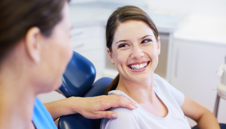Brunette woman smiles as she receives modern dental care