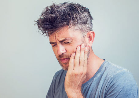 Man in grey shirt holding jaw