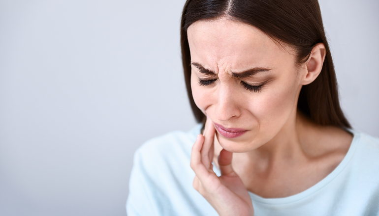 woman holding her jaw with phantom tooth pain